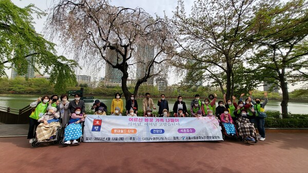 서울시립송파전문요양원 이용자와 가족들이 잠실 석촌호수에서 봄꽃을 배경으로 기념촬영을 하고 있다.사진제공 (사)나누며하나되기