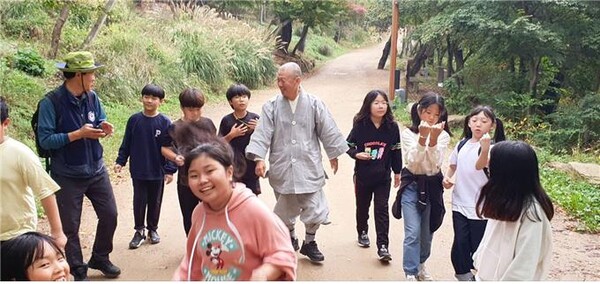 강화 전등사 어린이 숲체험학습에 참여한 선원초등학교 학생들이 전등사 주지 여암 스님과 함께 숲길을 걷고 있다.사진제공 불교환경연대 